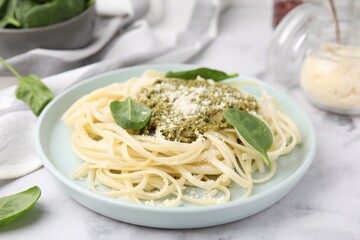 Tasty pasta with spinach, cheese and sauce on white marble table