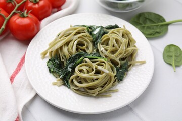 Tasty pasta with spinach and sauce on white tiled table