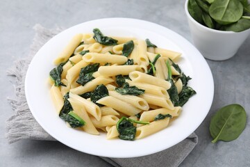 Tasty pasta with spinach and sauce on grey table