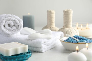 Spa composition. Towels, herbal bags, soap, sea salt and burning candles on light table