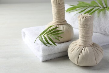 Spa composition. Herbal bags, towels and palm leaves on light table, space for text