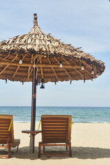 Straw sunshades and sunbeds on the empty pebble beach with sea in the background. Deserted beach...