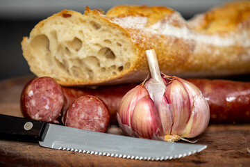 Rustic bread with salami and garlic on wooden board