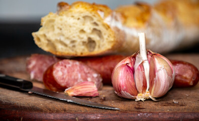 Rustic bread with salami and garlic on wooden board