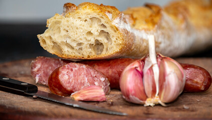 Rustic bread with salami and garlic on wooden board
