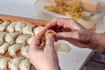 woman hands are making a damp dumpling. On the wooden counter