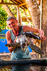 Man holds green sea turtle hawksbill turtle loggerhead sea turtle.