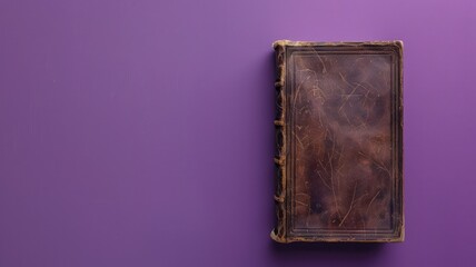 Aged leather-bound book closed on purple surface