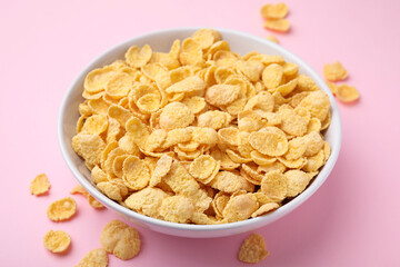 Breakfast cereal. Tasty corn flakes in bowl on pink table, closeup