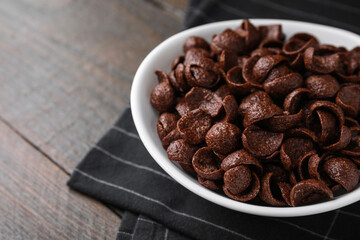 Breakfast cereal. Chocolate corn flakes in bowl on wooden table, closeup. Space for text