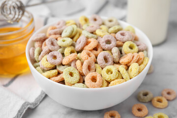 Tasty cereal rings in bowl on light table, closeup