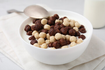 Breakfast cereal. Tasty corn balls with milk in bowl and spoon on table, closeup