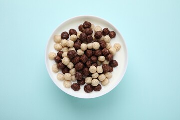 Breakfast cereal. Tasty corn balls with milk in bowl on light blue background, top view