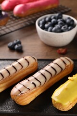 Different tasty glazed eclairs on table, closeup