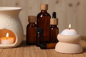 Different aromatherapy products and burning candles on table, closeup