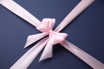 Pink satin ribbon with bow on blue background
