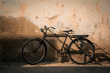 Vintage old bicycle leaning against dirty old wall background. Classic bike on decay wall with...