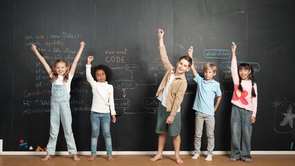 Diverse student raised hands up while standing at blackboard written with engineering prompt or...