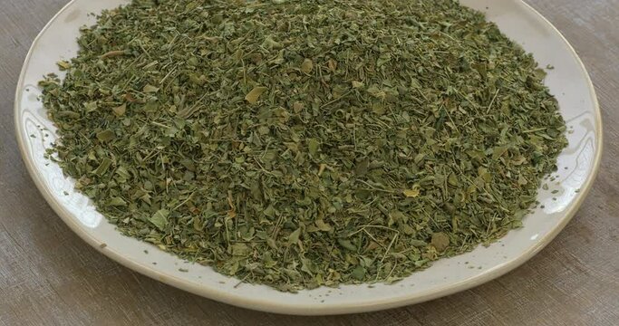 A heap of dried Moringa oleifera leaves on a plate. Tea from moringa leaves is a treatment for many diseases. Table spin.