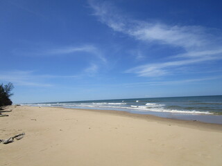 endless sand and sea under blue skies and wispy clouds