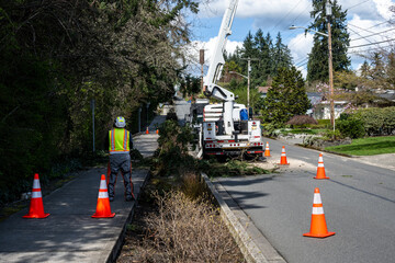 City street maintenance, bucket truck with boom arm extended, workman on ground looking up keeping watch on worker above  © knelson20
