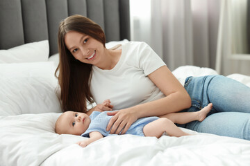 Naklejka premium Mother with her cute baby on bed indoors