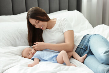 Naklejka premium Mother with her cute baby on bed indoors