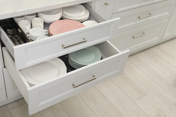 Clean plates, bowls, cutlery and cups in drawers indoors