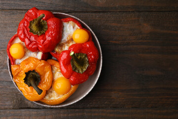 Delicious stuffed bell peppers with fried eggs on wooden table, top view. Space for text