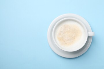 Aromatic coffee in cup on light blue background, top view. Space for text