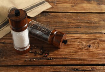 Salt and pepper shakers on wooden table, space for text