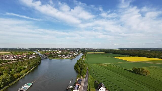 A scenic river flowing through fields and trees viewed from above and traffic on streets next to Mittellandkanal 4K FPV drone view Hanover Seelze Germany 