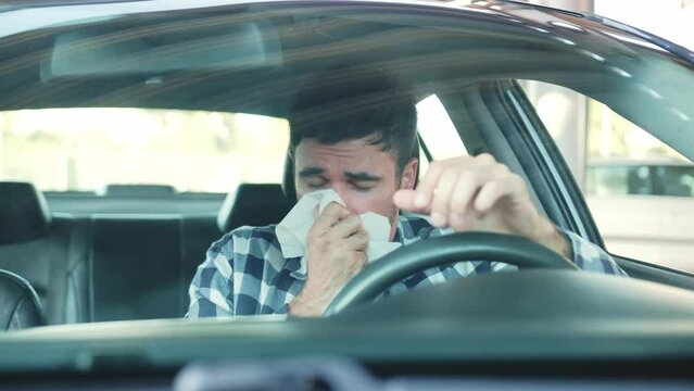 Sick guy has a runny nose while sitting in the car. Slow motion