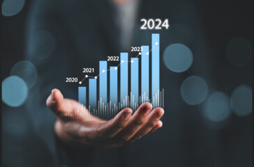 Businessman holding glowing virtual technical graph and chart for analysis stock market in 2024, technology investment and value investment concept.