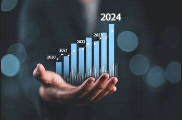 Businessman holding glowing virtual technical graph and chart for analysis stock market in 2024,...