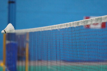 A shuttlecock over the net in the badminton court.