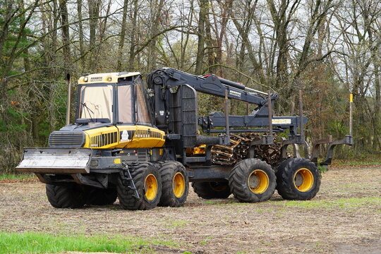 Ponsse Buffalo tree timber hauler sits next to a forest on a farm field.