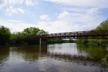 An iron steel walking path bridge stretches across a river. 
