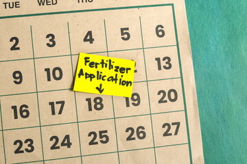 Fertilizer application schedule in farming and agriculture concept. Written reminder note on...