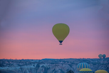 Sunrise in Cappadocia with colorful hot air balloons fly in sky over canyons, valleys morning...