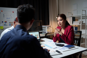 A group of young Asian business colleagues in a team discussion, startup business meeting or team brainstorming ideas analyze and discuss financial report situations.