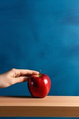 Red apple on wooden table against blue background