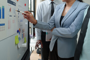 An operations manager presents a meeting to a team of economists using a whiteboard with growth...