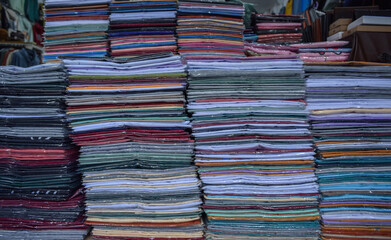 Stacks of colorful clothes and t-shirts in front of a clothing store