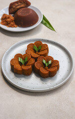 Bolu sakura karamel kukus, Indonesian traditional cake made from flour, eggs, caramelized sugar and other ingredients, served on a the round plate with grey background.