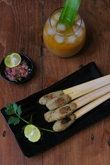 Flat lay of Sate Lilit. A traditional Balinese cuisine. It is kind of skewer or satay that usually made from Marlin or Tuna. Balinese Fish skewer or satay served with Sambal Matah and Herbal Drink.