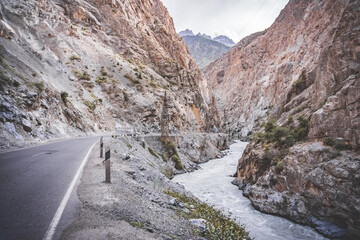 Road and river in a rocky gorge made of colored rocks in the Fan Mountains in Tajikistan
