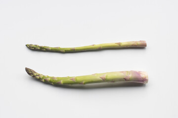 Fresh green asparagus isolated on a white background. A thick asparagus stalk in comparison with a thinner stalk. Asparagus is a perennial flowering plant species native to Eurasia. - Powered by Adobe
