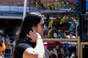 Mujer latina paseando por un mercado donde tienen jaulas de pájaros