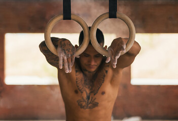 determined male athlete holding gymnastic rings